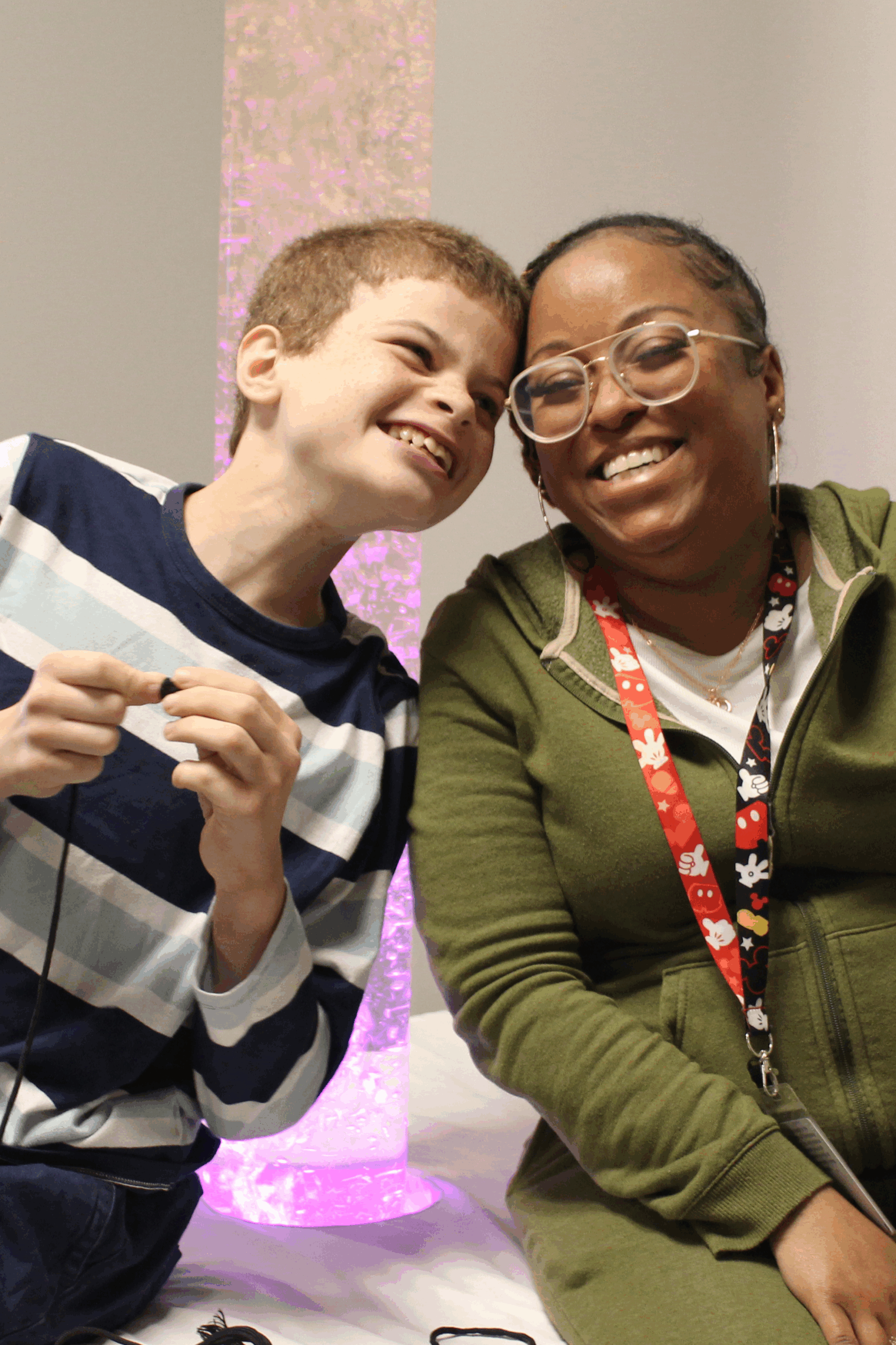 RespiteCenter2 Young boy smiles with the side of his head pressed against a staff member